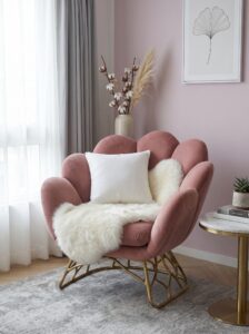 Cream wingback armchair with boucle upholstery, gold floor lamp, full-length mirror, marble side table, linen curtains, and patterned rug