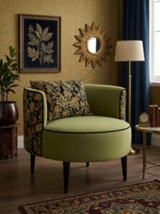 Low-profile cream boucle armchair with brown accent pillow, classic wall panels, large windows, dried branches, and luxury rug