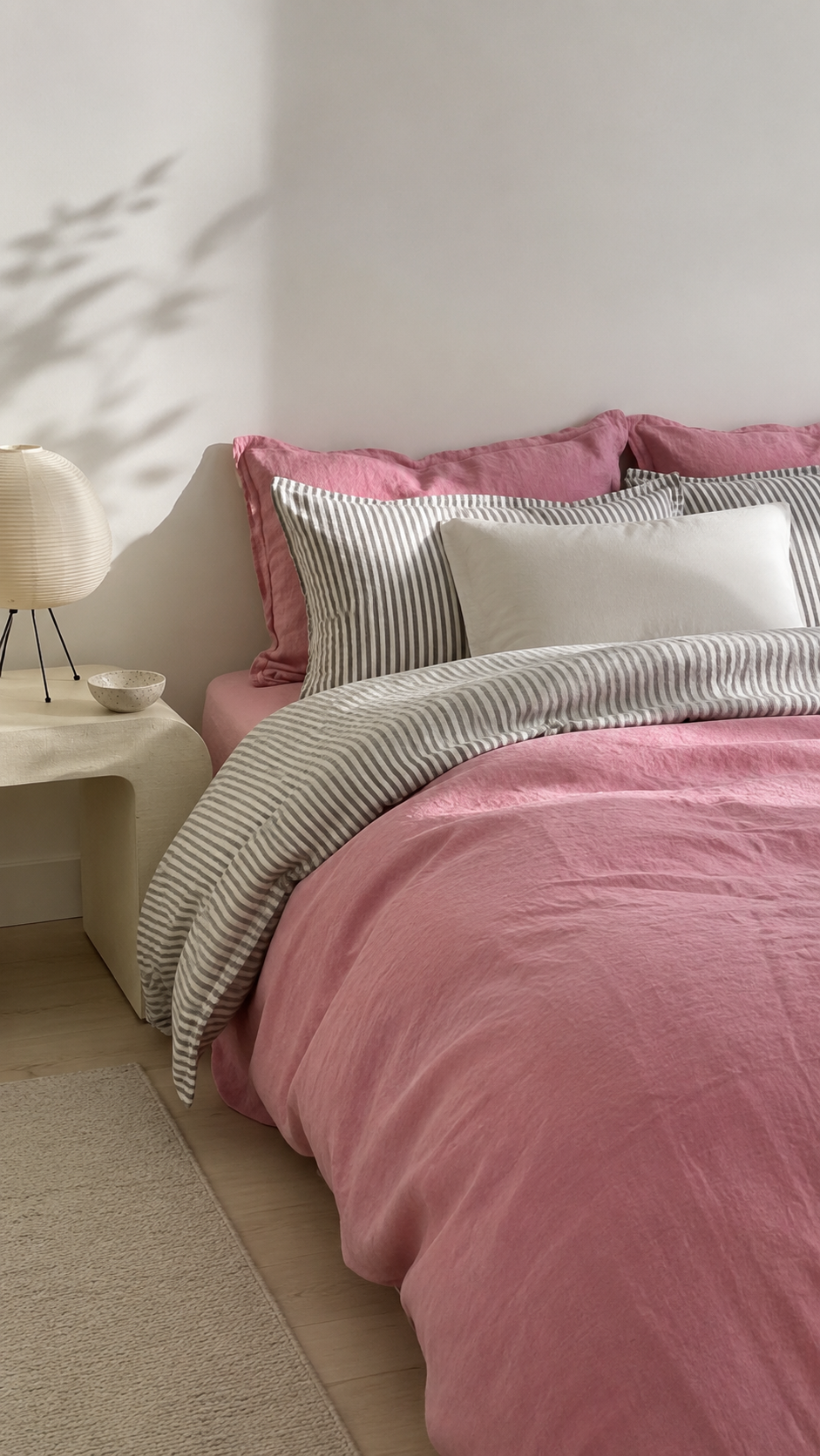 Dusty pink, gray, and white bedding color combo with striped layers, crisp white pillows, neutral decor, and soft feminine bedroom styling