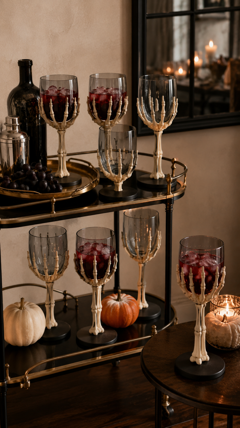 Dollar Tree Halloween bar cart with skeleton hand goblets, red drinks, smoky gray glasses, brass cart, black bottle, cocktail shaker, pumpkins, candle, mirror, and gothic party styling